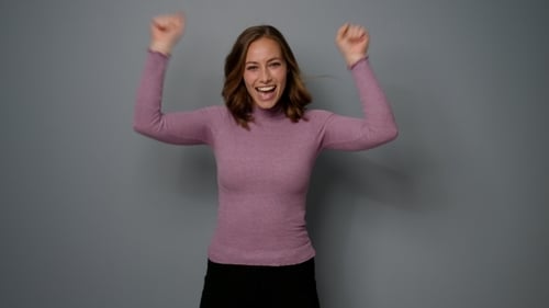 Smiling Woman Celebrating Success on Grey Background