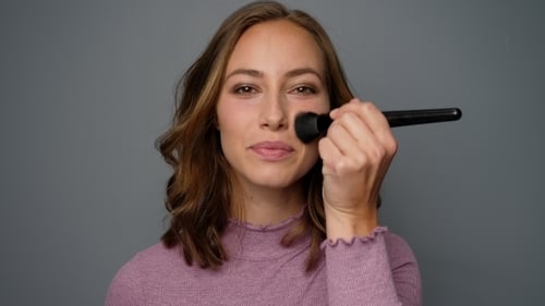 Woman Applies Makeup with Brush in Close Up Shot