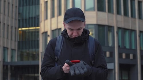 Young Man Typing Message on Screen Smartphone on Urban Street in Modern City
