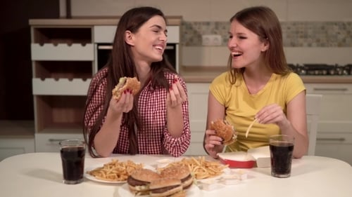 Two Women Eating Burgers and Fries at Home