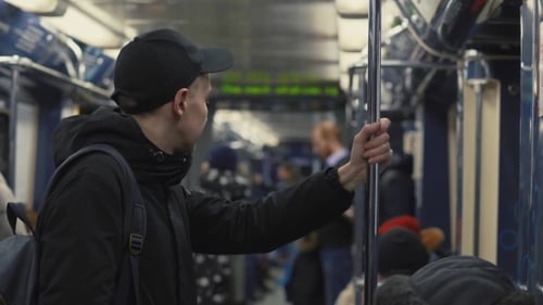 Man Student with Backpack Holding Handrail During Riding in Subway Train