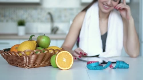 Woman With Fruit and Tablet in Kitchen