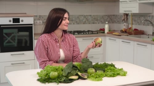 Woman with Fresh Vegetables and Apple in Kitchen