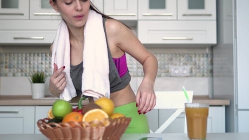Woman Looks at Phone with Juice and Fruit
