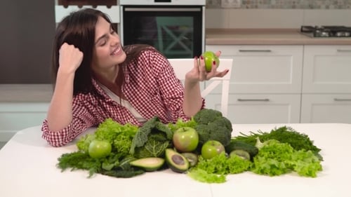 Woman Smiling with Fresh Green Produce in Kitchen
