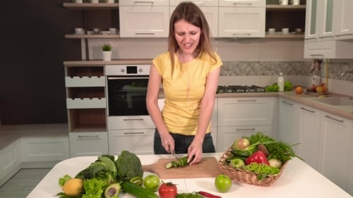 Young Woman Chopping Vegetables and Dancing in Kitchen
