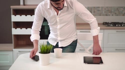 Man at Kitchen Table Looking at Tablet