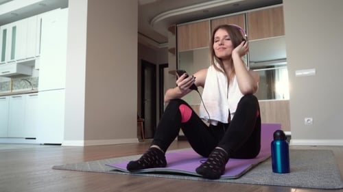 Relaxed Woman on Yoga Mat Listens to Music