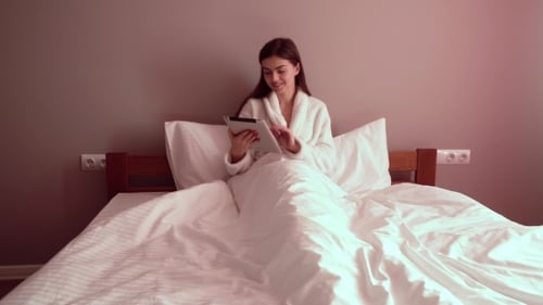 Woman Using Tablet in Bed at Home
