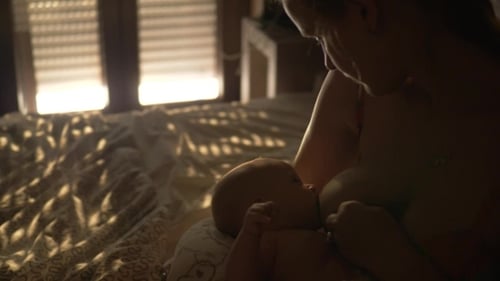 Baby Breastfeeding Held By Loving Adult Indoors