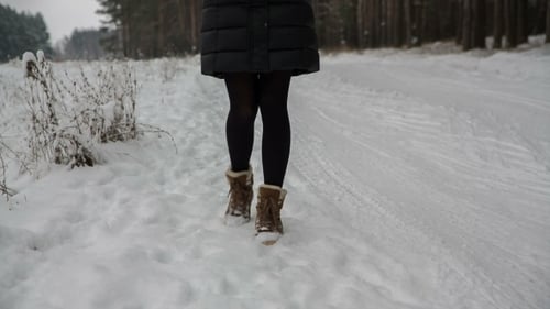 Woman Walks on Snowy Road in Winter