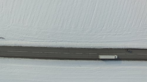 Road in Snowed Winter Field with Cars and Trucks