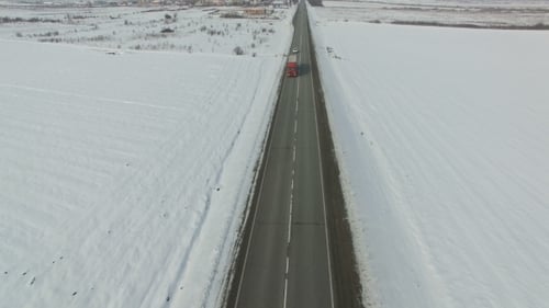 Luftaufnahme von Autos und Lastwagen, die an einem sonnigen Wintertag auf einer Straße fahren