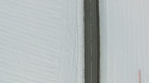 Straße im verschneiten Winterfeld mit Autos und Lastwagen