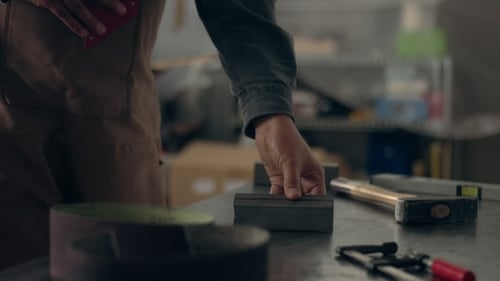 Worker in His Garage Preparing Two Metal Bricks for Welding