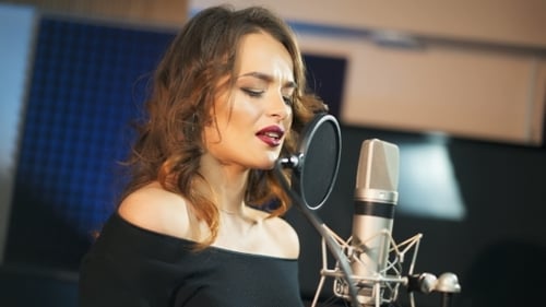 Beautiful Woman Singing Into a Large Microphone. Professional Recording Studio