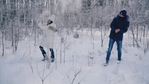Woman Throws Snow near Man in Snowy Forest