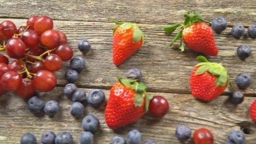 Tasty Summer Fruits on a Wooden Table Blueberries Grape Strawberries Blackberries Video