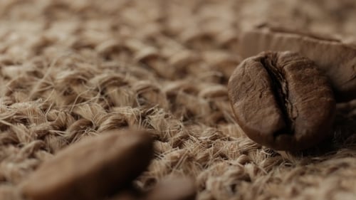 Macro Coffee Beans Falling Onto Burlap Surface