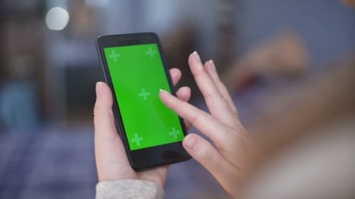 Woman Is Holding Smartphone with Green Screen in Cafe