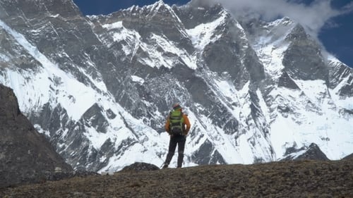 Man with Backpack Climb the Mountain Slope in the Himalayas