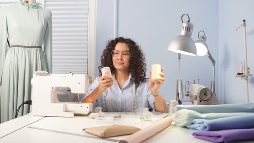Caucasian Woman Tailor Reeling Thread at Workplace