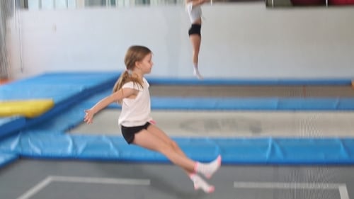 Girl Practices Gymnastics on Indoor Trampoline