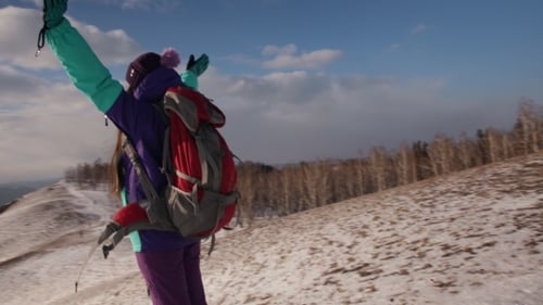 A Happy Woman Stands on Top of a Mountain and Enjoys the Sunset