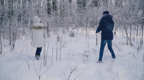 Couple Having a Snowball Fight in Snowy Woods