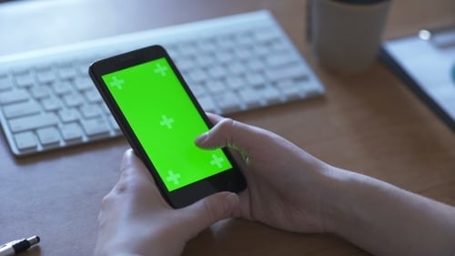 Woman Is Holding Smartphone with Green Screen in Home