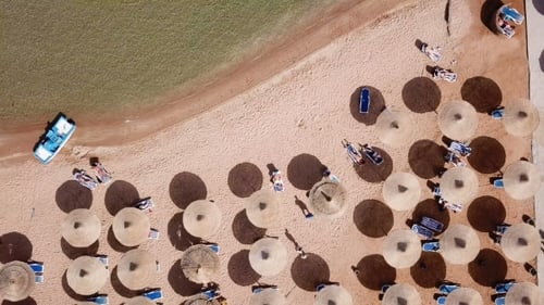 Umbrellas, Deck Chairs and Tourists Relaxing on the Beach
