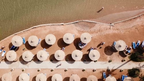 Umbrellas, Deck Chairs and Tourists Relaxing on the Beach. Aerial Top View.