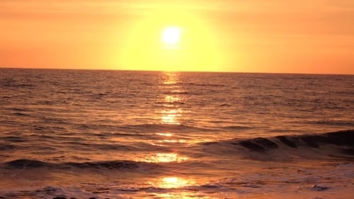 Sea Waves Rolled on a Sandy Beach in the Rays of the Setting Sun