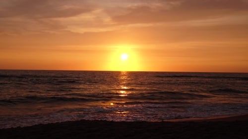 Sandy Beach with Choppy Waves of the Sea at Sunset