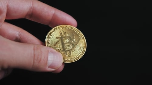 Männerhand hält goldenen Bitcoin auf schwarzem Hintergrund Litecoin Ethereum Neo