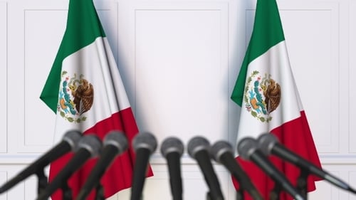 Conferencia de prensa oficial mexicana con banderas de México