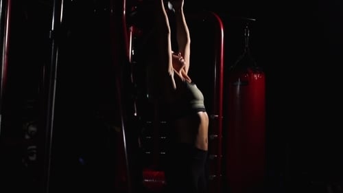 Fitness-Frau, die hängende Beinhebungen durchführt - eine der effektivsten Bauchmuskelübungen.