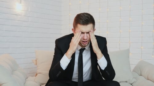 Man in Suit Holds Head in Pain