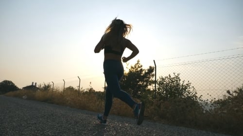 Following to Sporty Girl Jogging in Country Road at Sunrise. Young Woman Running Outdoors at Morning