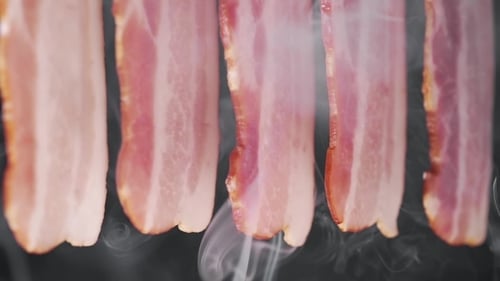 Geräucherte saftige und leckere Speckscheiben in den Rauchwolken
