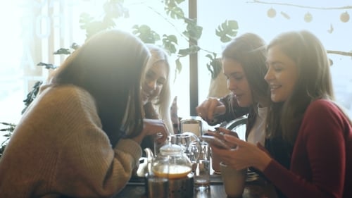 Four Friends Look at the Phone and Laugh