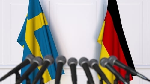 Swedish and German Flags Waving with Press Conference Microphones