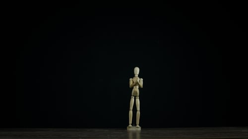 Stopmotion Wooden Figure Dummy Applauds in Studio on Black Background