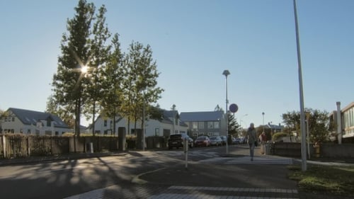 Mulher loira está cruzando uma passagem de pedestres na área suburbana em dia ensolarado de outono