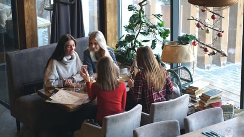 Group of Four Young People Sitting at Table in Restaurant and Having Fun While Dining.