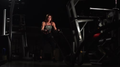 Sportlerin trainiert im Fitnessstudio mit schweren Seilen