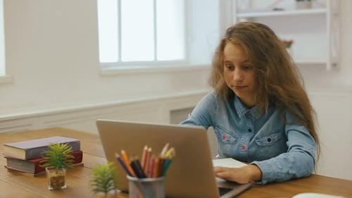 Young Girl with Laptop Computer Is Doing Homework. College Education. Tired Female Student Studying
