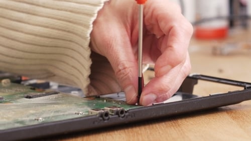 Hands Repairing Laptop with Screwdriver Close Up