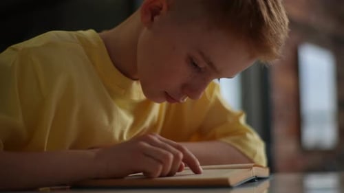 Boy Reading Intently Indoors During Daytime
