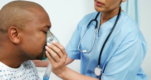 Healthcare Professional Assists Man with Oxygen Mask in Hospital